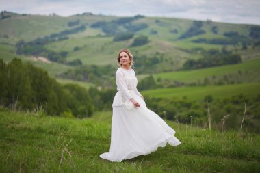 Gelin, dağların arka planında yürür, Altai 'de bir fotoğraf çekimi, gelinin bir portresi, beyaz elbiseli bir kız, boho tarzı.