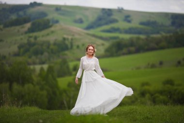 Gelin, dağların arka planında yürür, Altai 'de bir fotoğraf çekimi, gelinin bir portresi, beyaz elbiseli bir kız, boho tarzı.