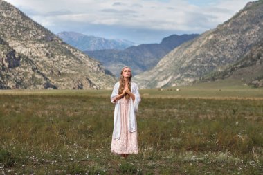 Peri masalı. Kibarca bir kız, çayırda, dağların arka planına doğru yürüyor. Tanrı 'yla konuşmak. Dua et..