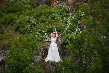 Gelin, dağların arka planında yürür, Altai 'de bir fotoğraf çekimi, gelinin bir portresi, beyaz elbiseli bir kız, boho tarzı.