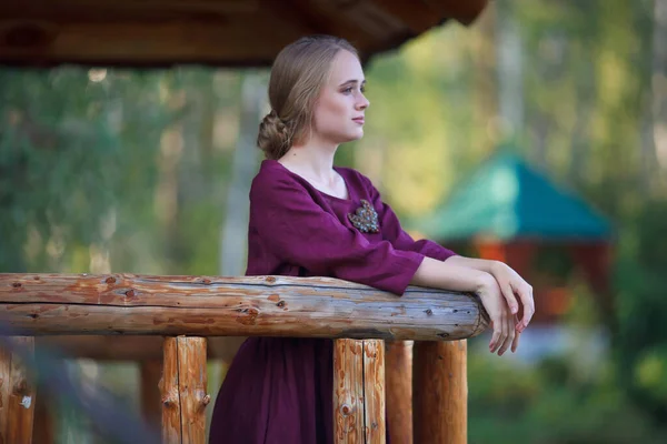 Girl Burgundy Dress Walks Suspended Wooden Bridge Smiling Blonde — Stock Photo, Image