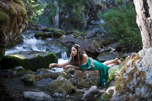 a tale of a nymph by a stream, a girl in a green dress on a background of a waterfall
