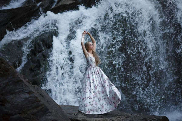 Girl on the background of a waterfall in the Altai mountains. Tale of the River Nymph. Fairytale photo shoot. The story of magic.