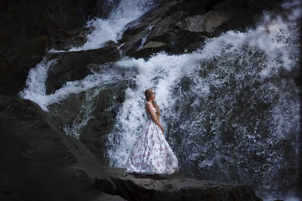 Girl on the background of a waterfall in the Altai mountains. Tale of the River Nymph. Fairytale photo shoot. The story of magic.