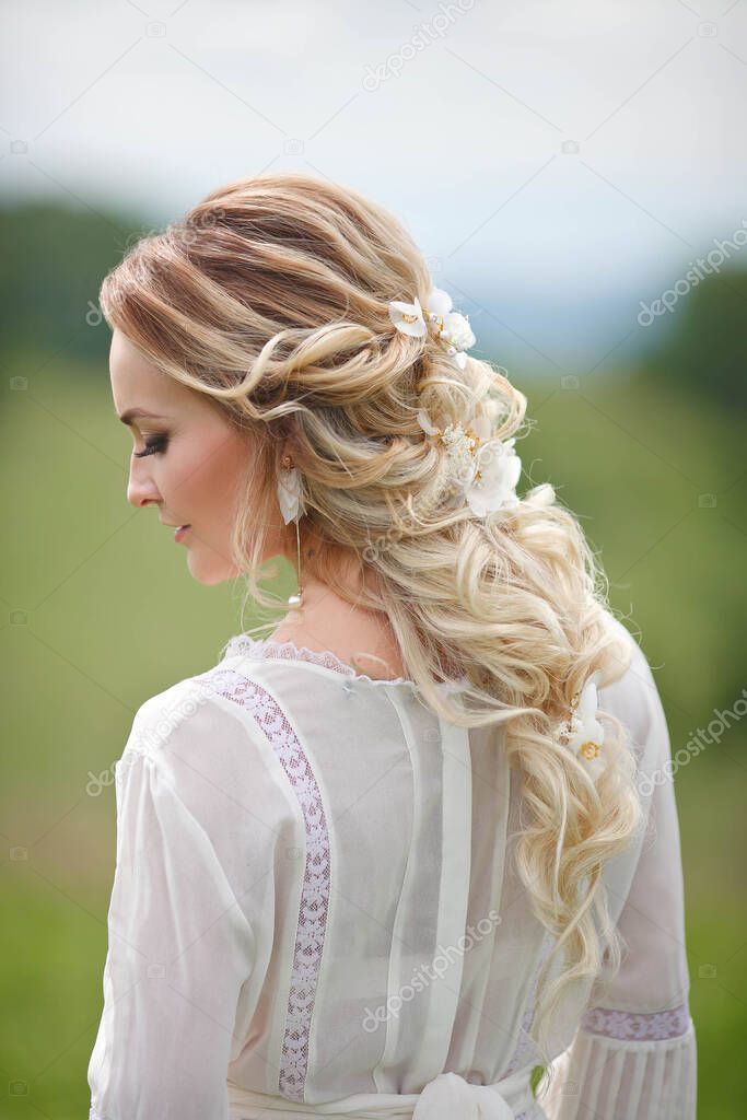 the bride walks in the field against the backdrop of the mountains, a photo shoot in Altai, a portrait of the bride, a girl in a white dress in the style of boho