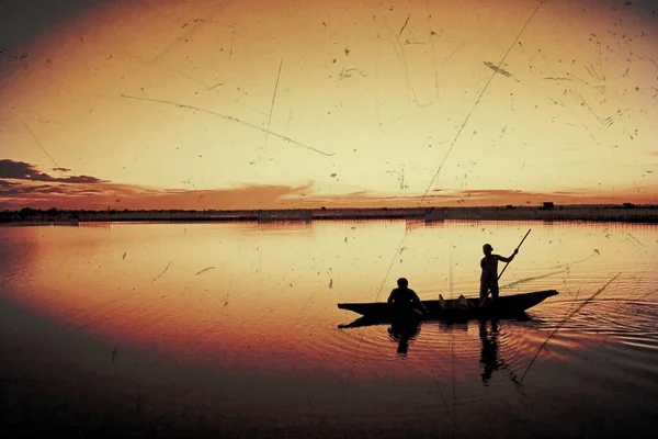 Jóvenes solitarios reman barcos en una puesta de sol — Foto de Stock