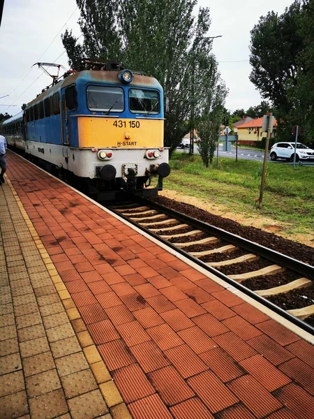 Um trem que desce trilhos de trem perto de uma estação — Fotografia de Stock