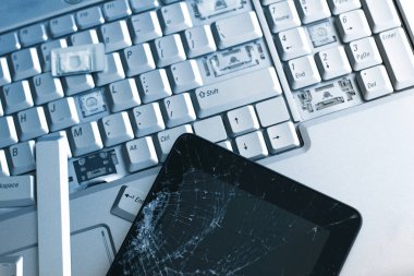 Gümüş bir dizüstü bilgisayar ile kırık bir klavye ve bir tablet ile bir kırık göstermek. Kırık dizüstü ve tablet kırık ekran parçası bir yakın çekim resim.