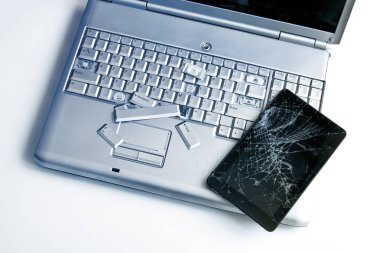 Gümüş bir dizüstü bilgisayar ile kırık bir klavye ve bir tablet ile bir kırık göstermek. Kırık dizüstü ve tablet kırık ekran parçası bir yakın çekim resim.
