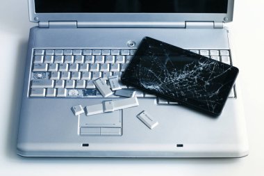 Gümüş bir dizüstü bilgisayar ile kırık bir klavye ve bir tablet ile bir kırık göstermek. Kırık dizüstü ve tablet kırık ekran parçası bir yakın çekim resim.