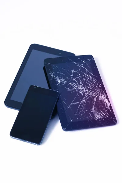 Fotos de pantalla agrietada en una tableta y un teléfono celular negro aislado en blanco. Tableta con pantalla dañada . —  Fotos de Stock