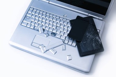 Kırık klavyeye sahip gümüş bir dizüstü bilgisayar, kırık ekranlı tablet ve siyah telefon. Tablette bozuk dizüstü bilgisayar ve kırık ekranın bir kısmının yakın çekim resmi.