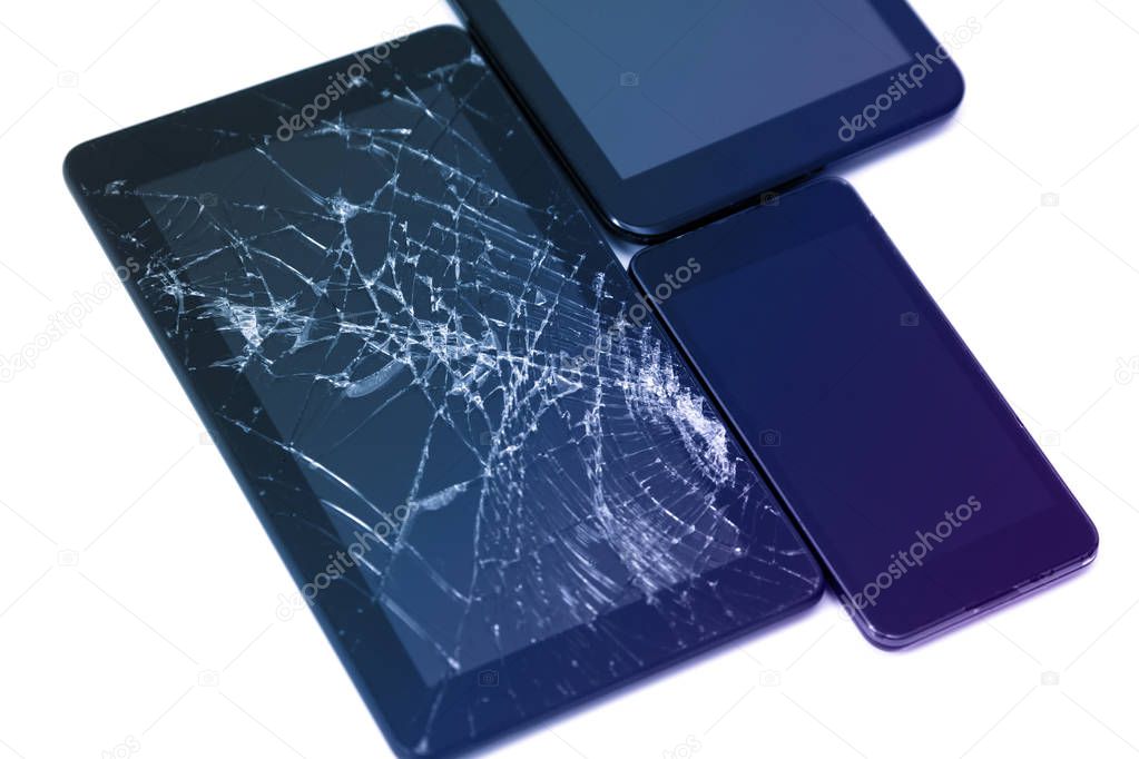 Photos of cracked display on a tablet and black cellphone isolated on white. Tablet with damaged screen.