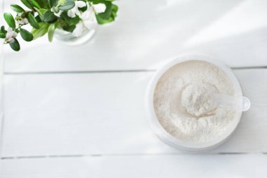 Gri arkaplanda toz halinde kolajen ya da protein. Sütlü içecek veya kolajen kokteyli yapmak için protein tozu. en üstteki görünüm