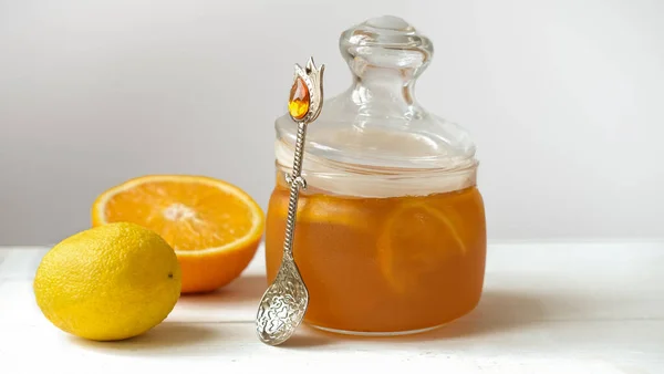 orange and lemon jelly or jam in a glass jar with spoon