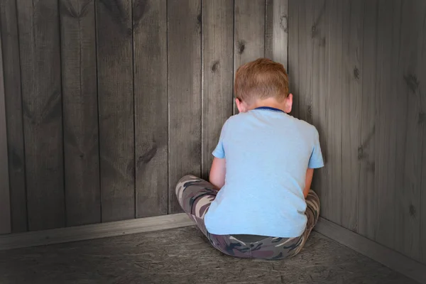 Sad little boy sitting in the corner turned his back. — Stock Photo, Image