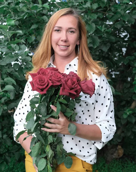 young beautiful teacher holding red roses. back to school concept. present from pupils. school teacher at the beginning of a school year. happy teacher with flowers.