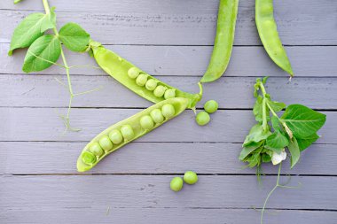 Şeffaf bir bardakta bezelye kabukları. Taze taze bezelyeler.