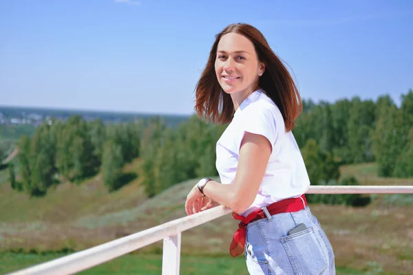 Mooie vrouw die op een balkon staat en glimlacht — Stockfoto