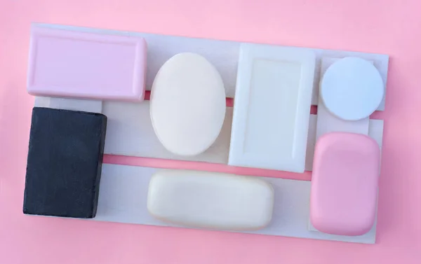 pink, white and black soap bars on a wooden tray. personal hygiene and face skin cleansing concept. variety of shapes of solid soap. fragranced soap.