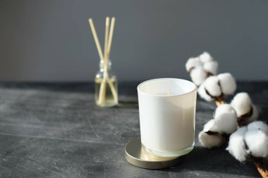  Higge ve aromaterapi konsepti. Aroma kamışı yayıcı, pamuk dalı ve evdeki gri masada beyaz soya mumu. minimal biçim kompozisyonu. Kış ve sonbahar havası