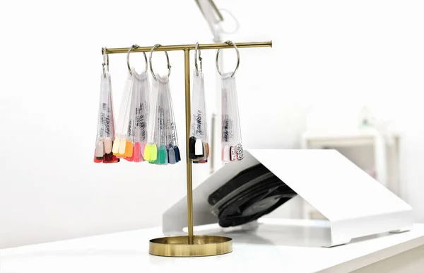 color palette of gel polish colors on a t-stand in beauty salon. picking up or making choice for nail color. professional service vacuum cleaner on the background.