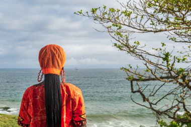 Gana 'dan geleneksel turuncu elbise giyen Afrikalı kadın Takoradi Gana Batı Afrika' da ufukta görünüyor.