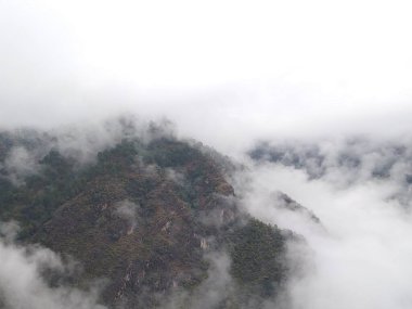 Bulutların ve sislerin arasındaki yüksek dağ