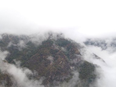 Bulutların ve sislerin arasındaki yüksek dağ