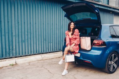 mavi bir araba ile elinde paketleri ile shooping gelen seksi giyinmiş ve giyinmiş bir genç kız