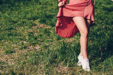 parkta genç bir bayan, kısa pembe kırmızı havlu, güzel bacaklar ile, çim çizmeler giymiş