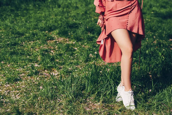 parkta genç bir bayan, kısa pembe kırmızı havlu, güzel bacaklar ile, çim çizmeler giymiş