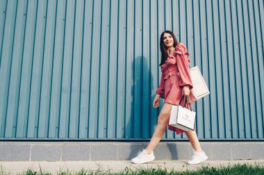 Genç ve güzel Bayan, alışveriş ile mutlu. Yaz cebinde elbise ve el paketleri.