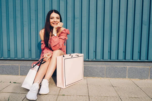 Genç ve güzel Bayan, alışveriş ile mutlu. Yaz cebinde elbise ve el paketleri.