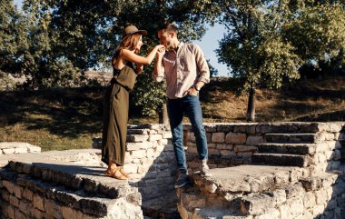 Bir bardak şarap ile çim açık havada yürüyüş şık çift. Erkek ve kadın birbirlerine bakarak ve birlikte açık havada yürüyüş.