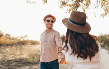 Bir bardak şarap ile çim açık havada yürüyüş şık çift. Erkek ve kadın birbirlerine bakarak ve birlikte açık havada yürüyüş.