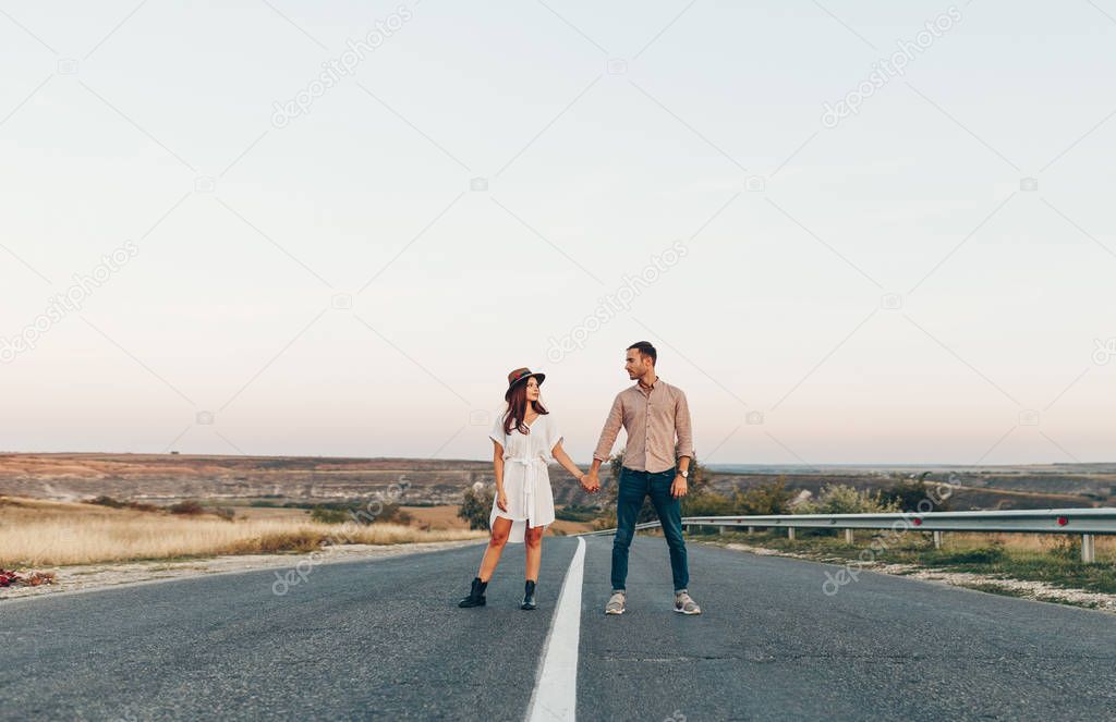 Rear view shot of young woman walking with her boyfriend on grass field. Couple enjoying a walk through grass land.
