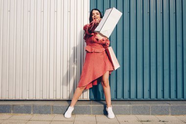 Genç ve hoş bir bayan, alışverişle mutlu. Yaz cebinde giyin ve çantalarını al. Metin yerleştirme yeri