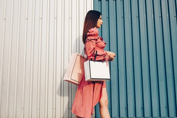 Genç ve hoş bir bayan, alışverişle mutlu. Yaz cebinde giyin ve çantalarını al. Metin yerleştirme yeri