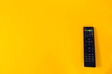 Pastel arka planda modern bir TV uzaktan kumandası. Üst görünüm, minimalizm