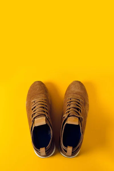 a pair of sport boots for men, brown on a yellow background. Discounts of shoes, seasonal discounts.