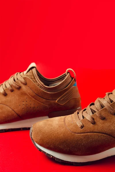 a pair of sport boots for men, brown on a red background. Discounts of shoes, seasonal discounts.