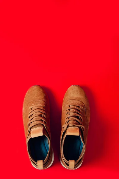 Erkekler için spor botlar bir çift, kırmızı arka planda kahverengi. Ayakkabı indirimler, mevsimlik indirimler.