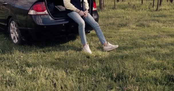 Un hombre sentado en el maletero del coche en el bosque — Vídeo de stock