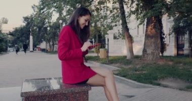 Şehirde cep telefonuyla duran, mesajlar yazan bir kadın..