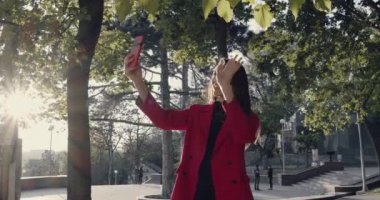Kadın karşıdan karşıya geçerken akıllı telefonu tutuyor ve yan bakıyor..