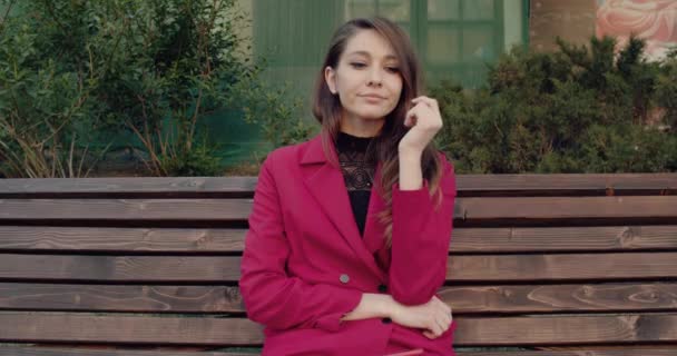 Una mujer sentada sola en el banco bajo el árbol en el parque . — Vídeos de Stock