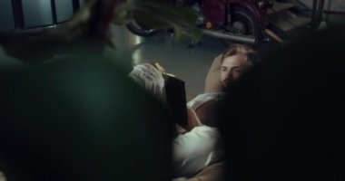 Bir adam kitap okurken, yaprakların arasından yakın çekim bir video.