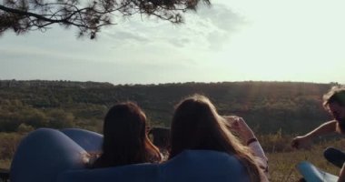 İki kız doğadaki bir oğlanın fotoğraflarını çekiyor..