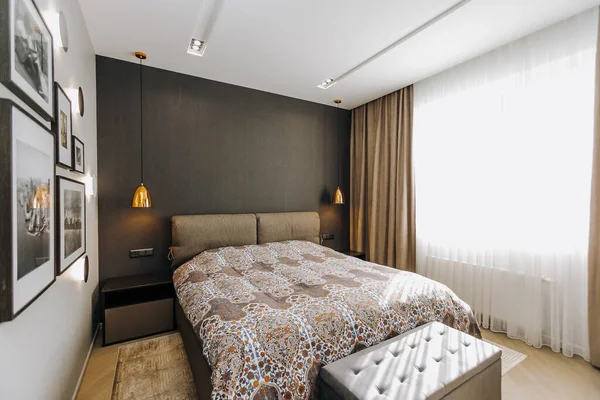 Şık ve davetkar bir yatak odası rahat bir yatak odası sergiliyor, sıcak renklerden faydalanıyor ve bol miktarda doğal ışık sağlıyor.